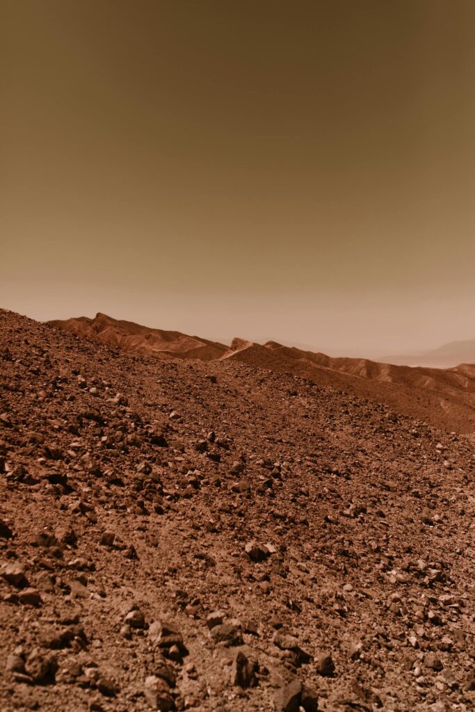 A barren and rocky desert landscape reminiscent of the planet Mars with a warm, dusty sky.
