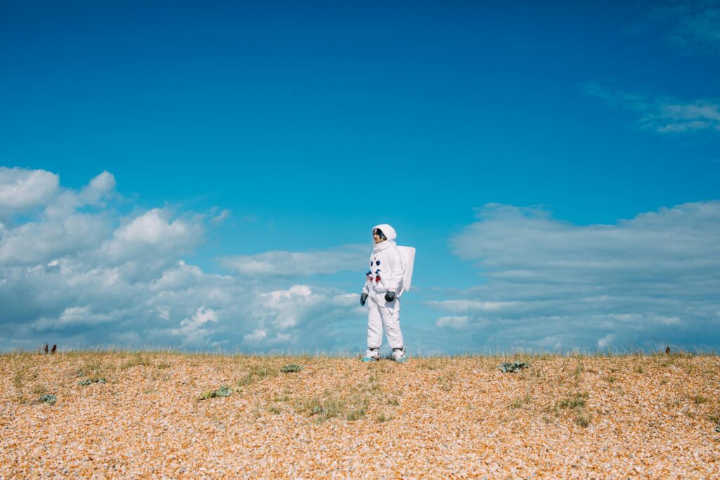An astronaut in a spacesuit stands alone in a desert landscape under a bright blue sky Earth’s Atmosphere Oxygenation