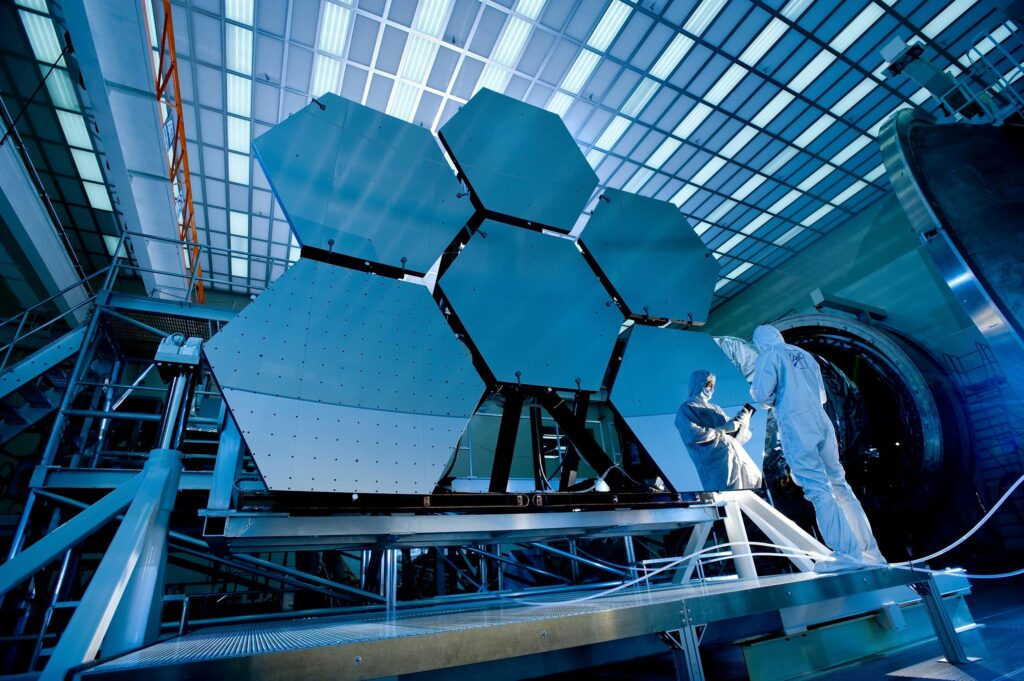 Engineers in protective suits work on telescopic mirrors in a high-tech lab. space printable metal
