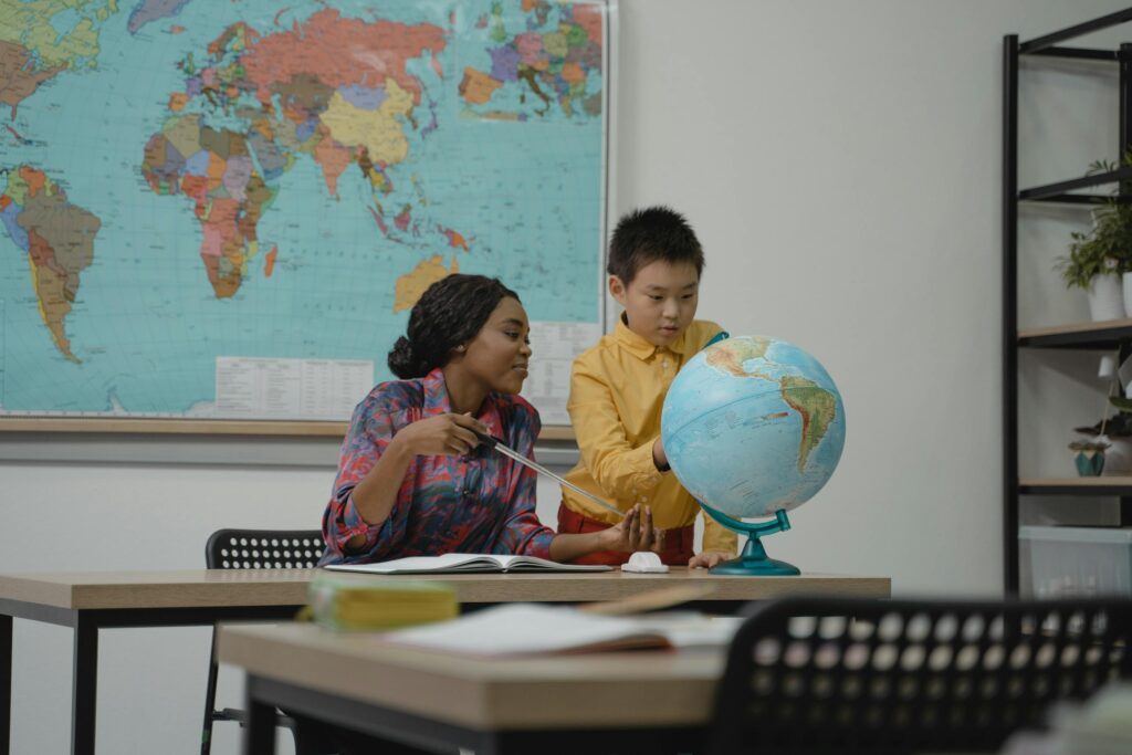 Teacher and student engaging with a globe in a classroom setting. discuss Earth science book